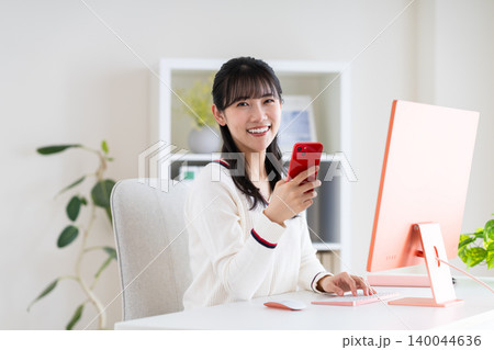 オフィスでスマホを使う若い女性 オフィスでスマホを使う若い女性 140044636