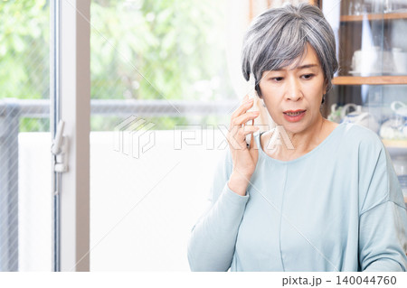 自宅でスマホ通話するシニア女性 自宅でスマホ通話するシニア女性 140044760