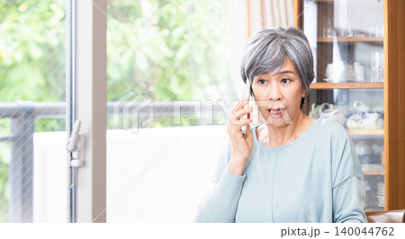 自宅でスマホ通話するシニア女性 自宅でスマホ通話するシニア女性 140044762