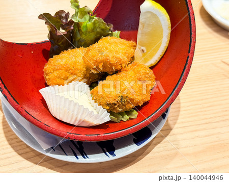 新鮮な牡蠣を揚げたカキフライとタルタルソースが乗ったお皿。レモンのくし切りを添えて。 140044946