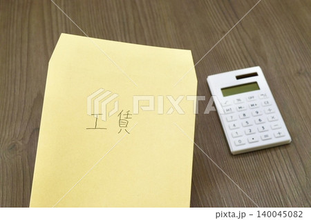 工賃と書かれた茶封筒と電卓 工賃と書かれた茶封筒と電卓 140045082