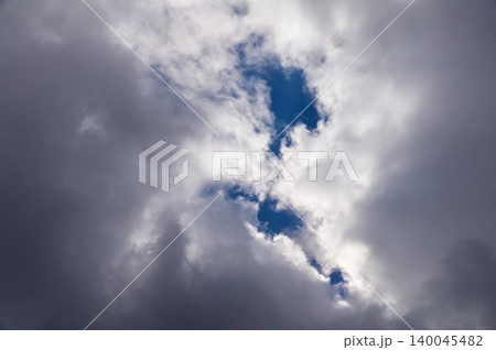 Dramatic cloudscape with gray clouds and the sunbeam, gray clouds cover the blue sky. Sunlight through the clouds . Nature concept 140045482