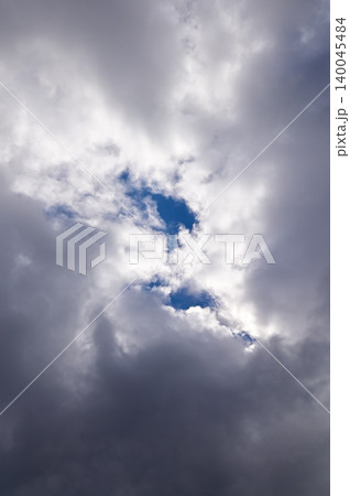 Dramatic cloudscape with gray clouds and the sunbeam, gray clouds cover the blue sky. Sunlight through the clouds . Nature concept 140045484