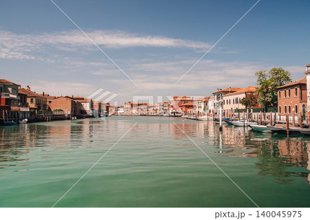 Wide Murano canal with lagoon glass factories and distant industrial view Wide Murano canal with lagoon glass factories and distant industrial view 140045975