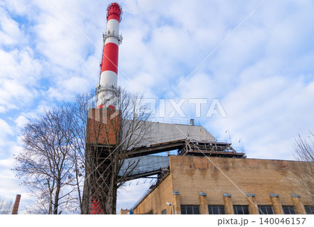 An upward angle photograph capturing brick manufacturing plant with prominent chimney and dramatic clouds An upward angle photograph capturing brick manufacturing plant with prominent chimney and dramatic clouds 140046157