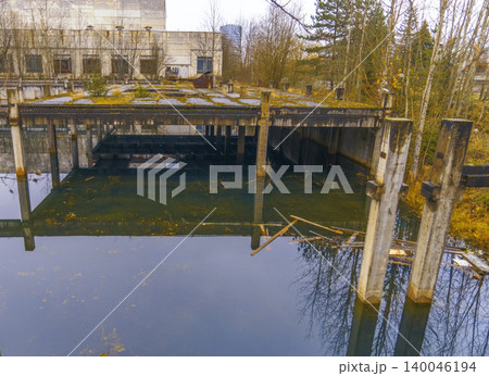 Decaying industrial site with nature reclaiming. Deserted industrial area overrun by moss and debris Decaying industrial site with nature reclaiming. Deserted industrial area overrun by moss and debris 140046194