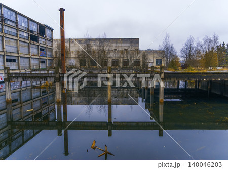 Tranquil water feature displaying factory backdrop with perfect symmetry and quiet ripples 140046203