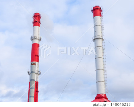 Industrial chimney silhouette. Vertical twin chimneys with vibrant red collars dominate landscape Industrial chimney silhouette. Vertical twin chimneys with vibrant red collars dominate landscape 140046213