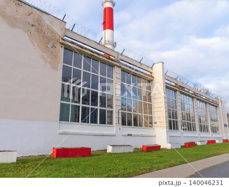 Scaled industrial wall features uniform windows and contrasting benches beneath gentle sky Scaled industrial wall features uniform windows and contrasting benches beneath gentle sky 140046231