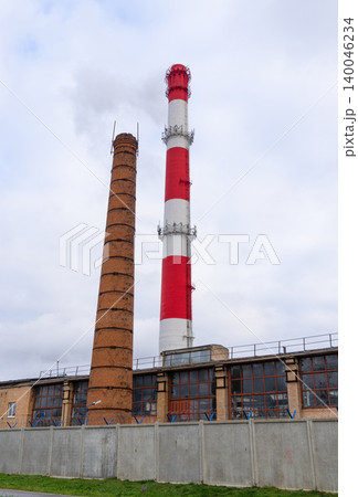 Weathered brick chimney paired with tall fence of steel highlights urban redevelopment potential 140046234