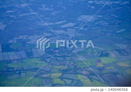 Looking through the airplane window with the view of cityscape under the clouds. Clouds above the city. Looking from aerial view. Nature and travel concept. Looking through the airplane window with the view of cityscape under the clouds. Clouds above the city. Looking from aerial view. Nature and travel concept. 140046568