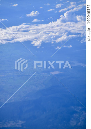 Looking through the airplane window with the view of cityscape under the clouds. Clouds above the city. Looking from aerial view. Nature and travel concept. Looking through the airplane window with the view of cityscape under the clouds. Clouds above the city. Looking from aerial view. Nature and travel concept. 140046573