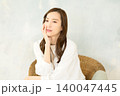 椅子に座って頬杖をつく 女性 140047445
