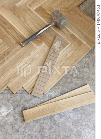 Beige parquet planks with adhesive and rubber mallet on floor during hardwood flooring installation Beige parquet planks with adhesive and rubber mallet on floor during hardwood flooring installation 140047453