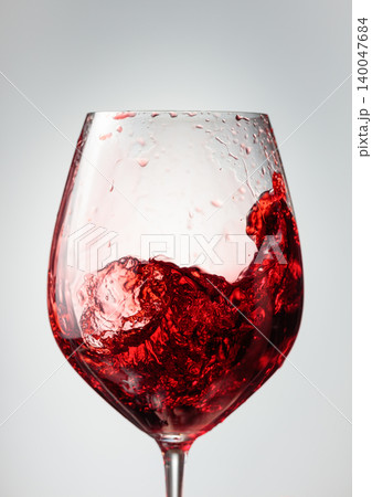 Wine glass with red liquid frozen in movement. 140047684