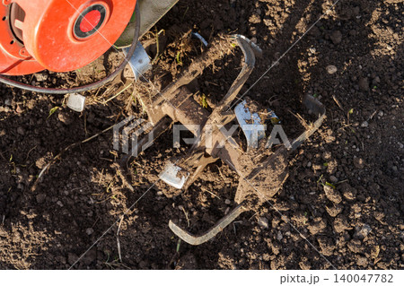 Rotary tiller blades cultivating soil close up 140047782