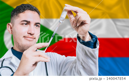 Doctor holding syringe on Comoros flag background. Medical professional holding syringe with Comorian flag in the background Doctor holding syringe on Comoros flag background. Medical professional holding syringe with Comorian flag in the background 140047854