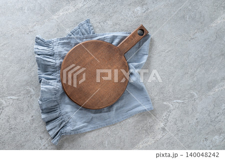 Wooden cutting board on blue linen napkin flat lay Wooden cutting board on blue linen napkin flat lay 140048242