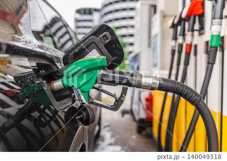 Refueling black car at gas station with green fuel nozzle on rainy day in Germany 140049318