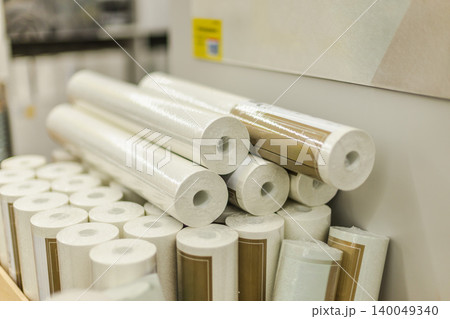White wallpaper rolls stacked on display shelf in home renovation and decoration store 140049340