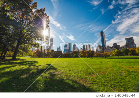 Central Park green lawn with Manhattan skyline and sunlight through trees on clear autumn day in New York City USA Central Park green lawn with Manhattan skyline and sunlight through trees on clear autumn day in New York City USA 140049344
