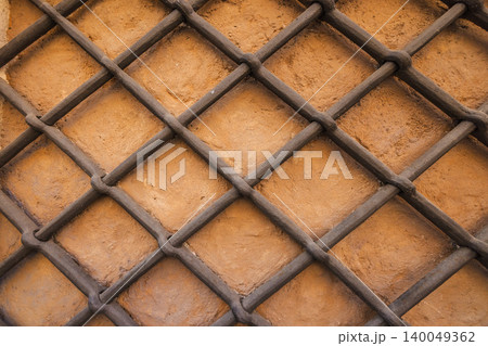 Rustic iron lattice pattern on warm stone wall of historic Roman building Rustic iron lattice pattern on warm stone wall of historic Roman building 140049362