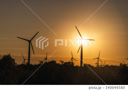 Wind turbines silhouetted at sunset over rural landscape producing renewable energy 140049380