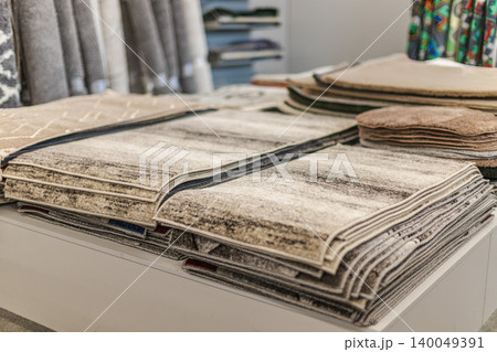 Folded carpet and rug samples displayed on table in home improvement store 140049391