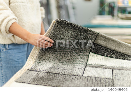 Woman choosing modern carpet in home decor and furnishing store Woman choosing modern carpet in home decor and furnishing store 140049403