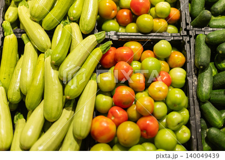 Fresh zucchini cucumbers and colorful tomatoes arranged in supermarket produce section, healthy organic vegetables for grocery shopping Fresh zucchini cucumbers and colorful tomatoes arranged in supermarket produce section, healthy organic vegetables for grocery shopping 140049439