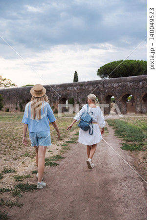 Mother and teenage daughter walking along path in Parco degli Acquedotti Rome toward ancient Roman aqueduct enjoying travel and family moment in Italy Mother and teenage daughter walking along path in Parco degli Acquedotti Rome toward ancient Roman aqueduct enjoying travel and family moment in Italy 140049523
