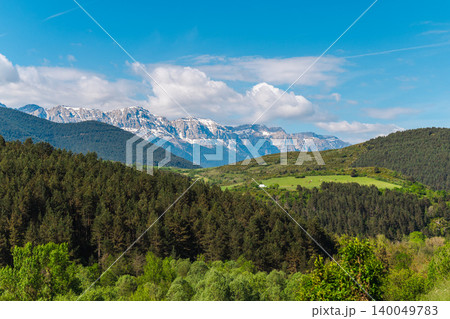 Snow capped Pyrenees mountain range above dense forest and green valley in Catalonia under dramatic clouds and blue sky Snow capped Pyrenees mountain range above dense forest and green valley in Catalonia under dramatic clouds and blue sky 140049783