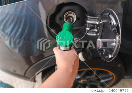Hand refueling modern car with green fuel nozzle at gas station close up transportation and energy concept 140049793