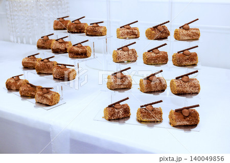 Desserts are arranged on stands at celebration event each dessert has piece of chocolate stick on top. Desserts are arranged on stands at celebration event each dessert has piece of chocolate stick on top. 140049856