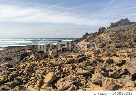 A sea view beyond a stark desert landscape on Lanzarote, capturing the islands raw volcanic beauty A sea view beyond a stark desert landscape on Lanzarote, capturing the islands raw volcanic beauty 140050252