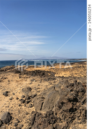 A sea view beyond a stark desert landscape on Lanzarote, capturing the islands raw volcanic beauty A sea view beyond a stark desert landscape on Lanzarote, capturing the islands raw volcanic beauty 140050254
