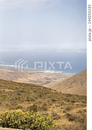 Wide view of Lanzarote desert landscape with volcanic hills and stark island beauty Wide view of Lanzarote desert landscape with volcanic hills and stark island beauty 140050285
