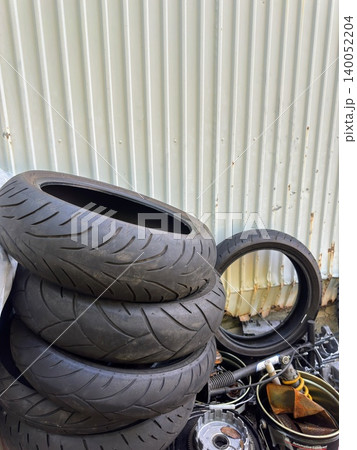 積み上げられた中古のバイク用タイヤと廃材 140052204