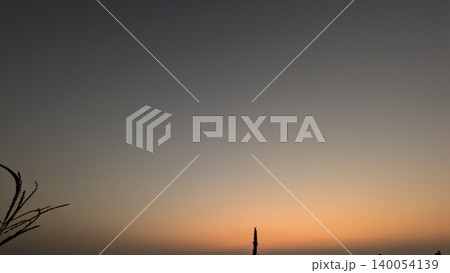 Silhouette of small plants stands against a smooth dark gradient sky backdrop. A soft orange sunrise glow transitions into deep twilight gray tones, offering a clean nature background layout. Silhouette of small plants stands against a smooth dark gradient sky backdrop. A soft orange sunrise glow transitions into deep twilight gray tones, offering a clean nature background layout. 140054139