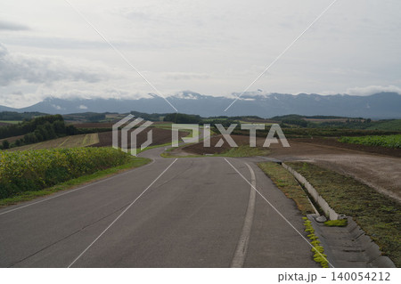 北海道の美瑛のドライブの丘と曲線道路、雲かかる十勝岳連峰、9月の初秋の田園パノラマ 140054212