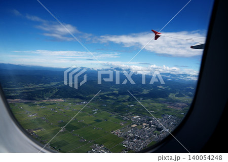 北海道上空から機内窓越しに望む田園地帯と山並み、飛行機の翼、8月の真夏の空撮絶景 140054248
