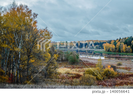 Autumn landscape with colorful trees and calm river under cloudy sky in rural area Autumn landscape with colorful trees and calm river under cloudy sky in rural area 140056641