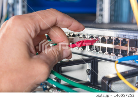 hand of engineer plugging in ethernet cable into server switch p hand of engineer plugging in ethernet cable into server switch p 140057252