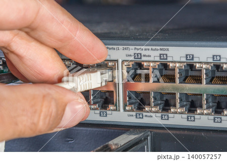 hand of engineer plugging in ethernet cable into server switch p 140057257