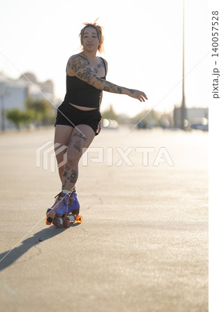 Tattooed woman enjoying roller skating in urban setting Tattooed woman enjoying roller skating in urban setting 140057528