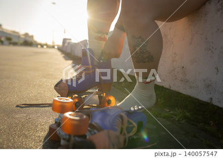 Person lacing up roller skate at sunset outdoors 140057547