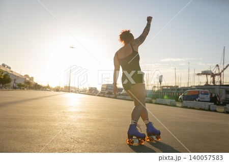 Woman roller skating raising fist toward sunset 140057583