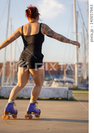 Tattooed woman roller skating enjoying freedom outdoors Tattooed woman roller skating enjoying freedom outdoors 140057663