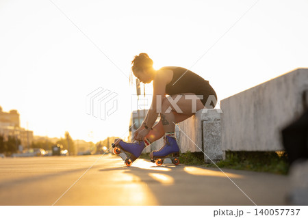 Woman tying roller skate laces during golden hour 140057737
