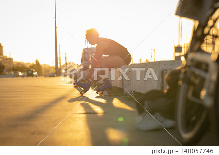 Woman tying roller skates at golden hour 140057746